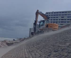 Services de travaux publics avec une pelle sur pneus de la société duquenoy travaux publics pour un chantier sur une digue de plage